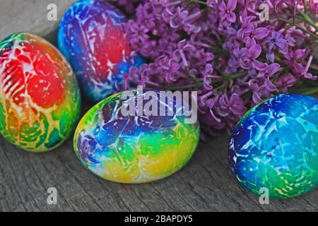 Easter composition. Art designed eggs with lilac on wooden background. Stock Photo