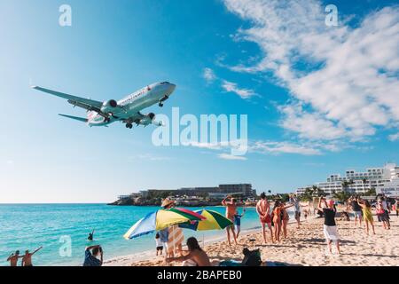 An American Airlines Boeing 737-800 flies low over Maho Beach on approach to St. Maarten International Airport Stock Photo
