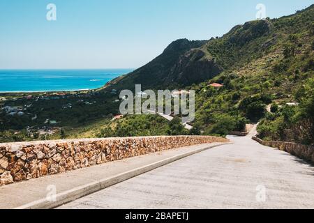 A scenic road down toward the sea with a small stone wall on the island of St Barthélemy, French Caribbean Stock Photo