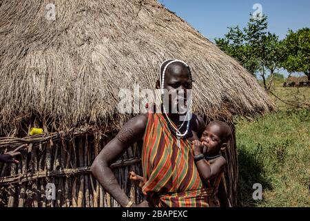 Woman of the Mursi tribe with clay lip disc as body  holding a baby, Mago National Park, Southern Ethiopia, Africa Stock Photo