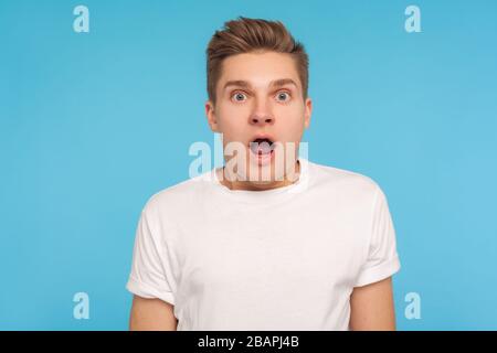 Wow, unbelievable! Portrait of astonished man in casual white t-shirt looking at camera with mouth open in amazement, scared and shocked by crazy news Stock Photo