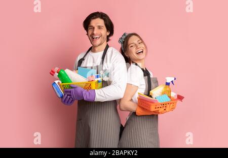 Team of janitors with cleaning supplies on pink background Stock Photo