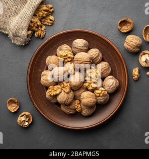 Nuts. Walnut kernels and whole walnuts on dark stone table. Top view, flat lay. Stock Photo