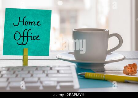 Remote work at home during the Coronavirus epidemic. A card with the words "Home Office" and a cup of coffee, pen, computer keyboard Stock Photo