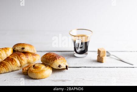 Breakfast with croissants, cinnamon buns and chocolate cookies, fresh orange juice and coffee on the side on a white background. Stock Photo