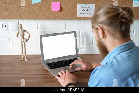 Young man using laptop e learning browsing internet with mock up blank screen. Stock Photo