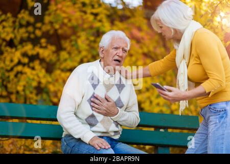 Suffering senior man consoled by elderly woman