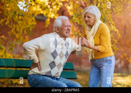 Suffering senior man consoled by elderly woman