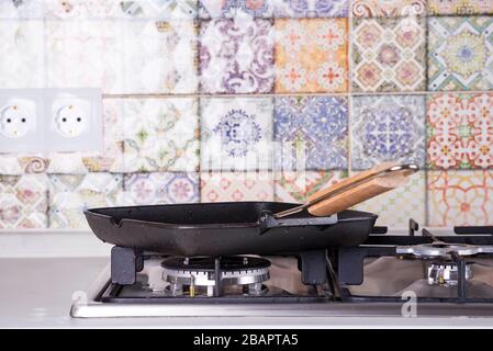Empty frying grill pan on a gas stove on the background of old colored tiles. Kitchen interier Stock Photo