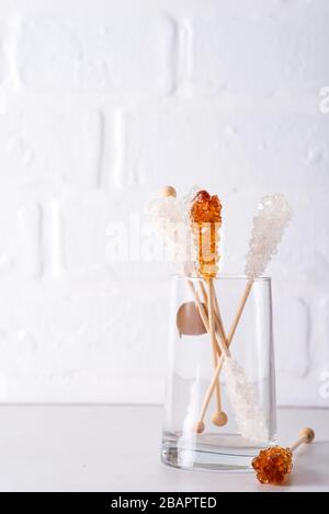 Candy brown and white sugar on a sticks in glass on white background. Stock Photo