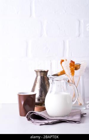 Jug of milk and ground coffee for making a drink at home on a stone countertop against a white kitchen wall Stock Photo