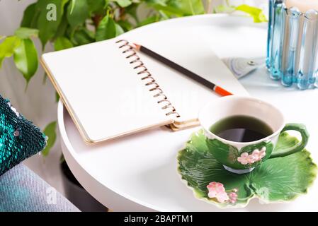 a cup of herbal tea on a table with notepad and candle . Bedroom interior Stock Photo