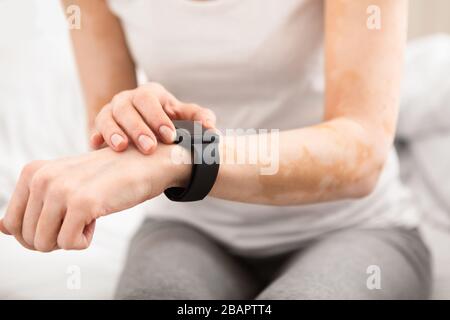 Woman with modern watches measuring pulse on hand Stock Photo
