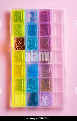 Beads in organizer boxes on pink background. Handmade accessories. Top view Stock Photo