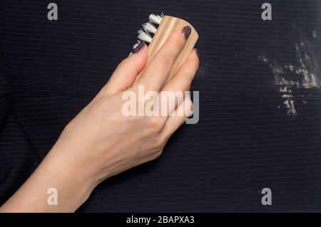 Dry cleaning: a woman hand with holding a clothes brush for cleaning clothes from dirty Stock Photo