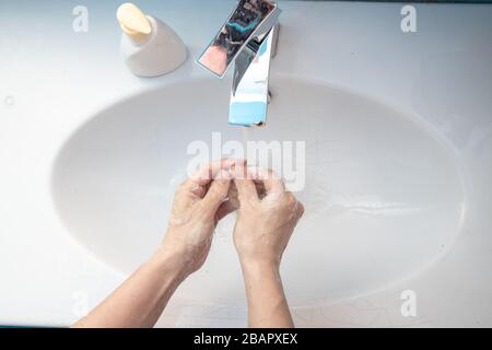 Top above close up view woman standing in bathroom washing her hands under flowing water flushing soap. Stop corona virus covid19, keep personal hygie Stock Photo