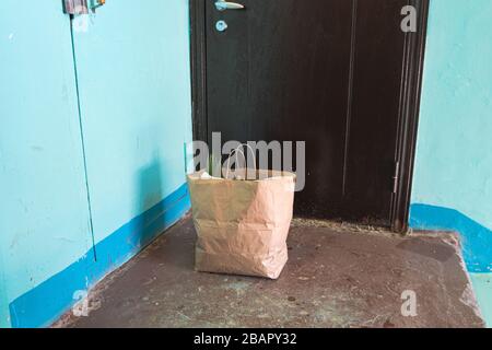 Delivery during quarantine. Self-isolation. Social Services. A paper bag with goods and food in front of the door, the concept of neighborhood Quarant Stock Photo