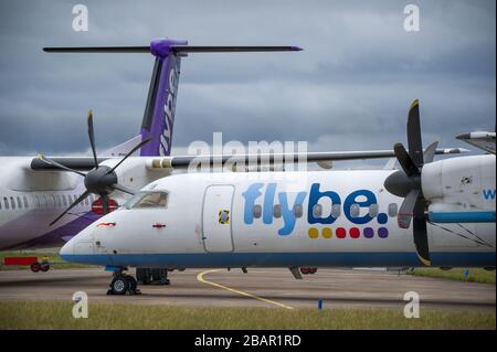 Glasgow, UK. 27 March 2020. Pictured: Grounded Flybe De Havilland Canada Dash 8 Q400 Aircraft seen parked up on the tarmac by the Emergency Rendezvous point at Glasgow Airport.  The Coronavirus Pandemic has been responsible for the UK shutdown aviation bringing Glasgow Airport to look more like a ghost town. Credit: Colin Fisher/Alamy Live News. Stock Photo