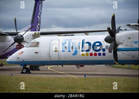 Glasgow, UK. 27 March 2020. Pictured: Grounded Flybe De Havilland Canada Dash 8 Q400 Aircraft seen parked up on the tarmac by the Emergency Rendezvous point at Glasgow Airport.  The Coronavirus Pandemic has been responsible for the UK shutdown aviation bringing Glasgow Airport to look more like a ghost town. Credit: Colin Fisher/Alamy Live News. Stock Photo