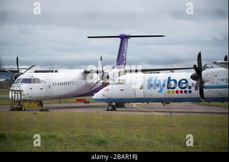 Glasgow, UK. 27 March 2020. Pictured: Grounded Flybe De Havilland Canada Dash 8 Q400 Aircraft seen parked up on the tarmac by the Emergency Rendezvous point at Glasgow Airport.  The Coronavirus Pandemic has been responsible for the UK shutdown aviation bringing Glasgow Airport to look more like a ghost town. Credit: Colin Fisher/Alamy Live News. Stock Photo