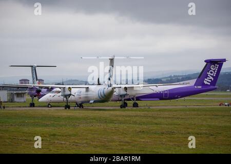 Glasgow, UK. 27 March 2020. Pictured: Grounded Flybe De Havilland Canada Dash 8 Q400 Aircraft seen parked up on the tarmac by the Emergency Rendezvous point at Glasgow Airport.  The Coronavirus Pandemic has been responsible for the UK shutdown aviation bringing Glasgow Airport to look more like a ghost town. Credit: Colin Fisher/Alamy Live News. Stock Photo