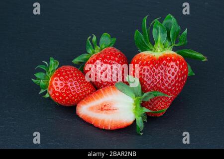 fresh garden strawberry fruits isolated on black slate plate closeup Stock Photo