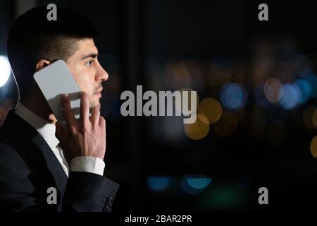 Serious Businessman Talking On Mobile Phone Standing In Office, Side-View Stock Photo