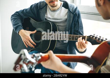 Learning to play the guitar. The teacher explains to the student the basics of playing the guitar. Individual home schooling or extracurricular lesson Stock Photo