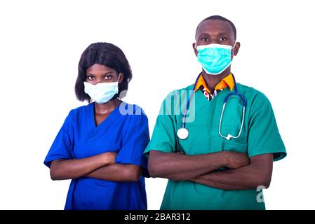 two young doctors in uniform wearing medical masks and crossing their arms at the hospital looking at the camera. Stock Photo