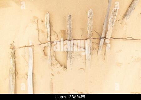 Close up of part buried wooden fence on sandy beach , Formby, England,UK Stock Photo