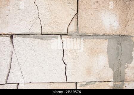 Cracks on the white wall blocks. The destruction of the wall. Background texture. Stock Photo
