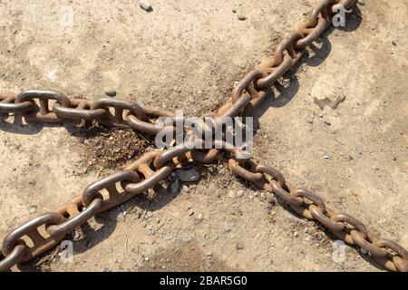 Old rusty chains on to the the ground, used to winch fishing boats up the beach in the village of Cadgwith, Cornwall, England Stock Photo