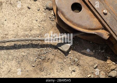 Old wire rope cable, block, pulley fixed to the the ground, used to winch fishing boats up the beach in the village of Cadgwith, Cornwall, England Stock Photo