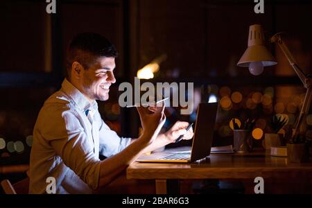 Smiling Businessman Using Voice Assistant In Modern Office At Night Stock Photo