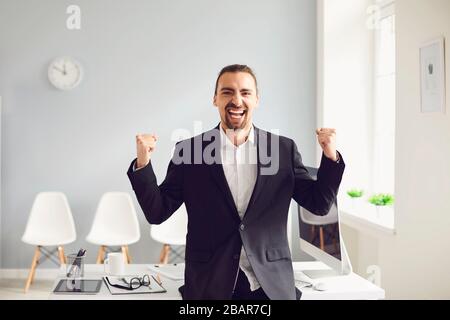 Excited ethnic businessman celebrating success in office Stock Photo