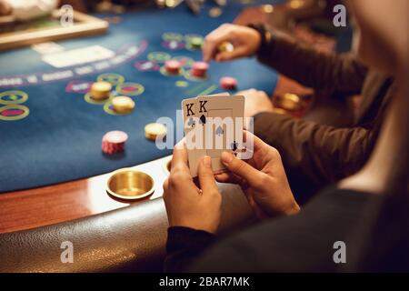 Close-up hands of a poker player checking cards in a casino. Stock Photo