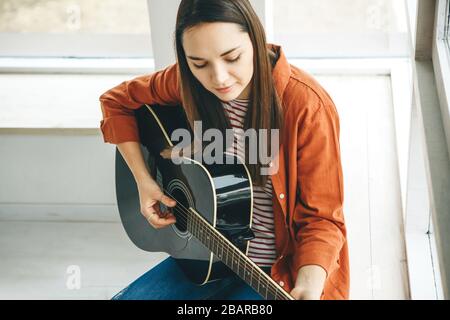 Learning to play the guitar. The teacher explains to the student the basics of playing the guitar. Individual home schooling or extracurricular lessons. Stock Photo