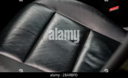 Black perforated leather car seat with macro close up isolated details. White line leather contour, beautiful stitch, ventilated seats, low mileage. Stock Photo