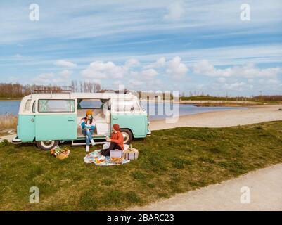 Noordoostpolder Netherlands April 2019, Classic Green and white VW Camper Van parked with couple watching the Sunrise over the meadow during Spring Stock Photo