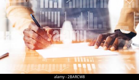 African American employee doing paperwork at desk. Collage with double exposure of business data on transparent screen Stock Photo
