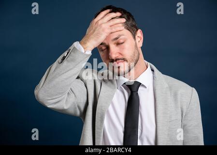 Portrait of business young handsome male making problem gesture on blue background Stock Photo