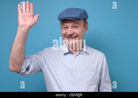 Mature hispanic man waving hand welcoming his friend Stock Photo