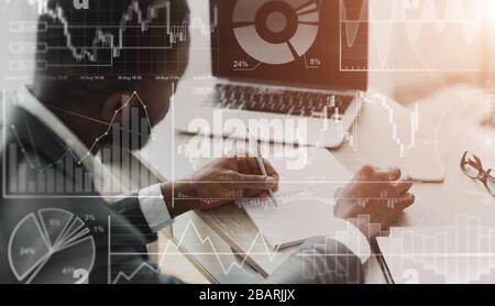 African American businessman with laptop working in office, collage with financial data on imaginary screen Stock Photo