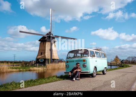 Alkmaar Netherlands April 2019, classic old vintage car van parked by historical windmill in Holland, Classic Minty Green and white VW Camper Van Stock Photo