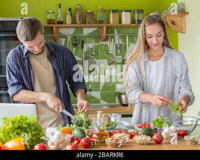 Millennial couple preparing healthy vegetarian salad enjoying process Stock Photo