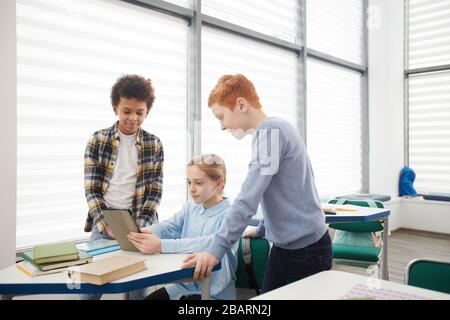 Multi-ethnic group of children using digital tablet and internet devices in school classroom, copy space Stock Photo