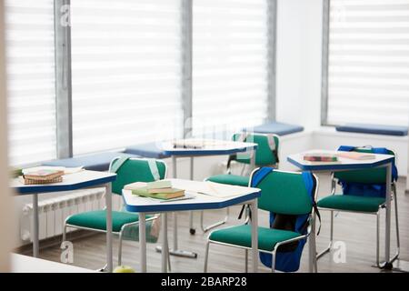 Background image of empty classroom interior in modern school building, rows of desks with books, copy space Stock Photo