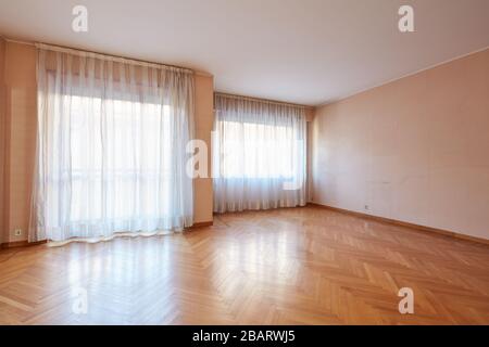 Empty large room with wooden floor and white curtains in apartment interior Stock Photo