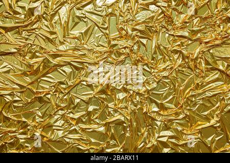 Crumpled, golden metallic paper texture background Stock Photo