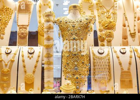 DUBAI, UNITED ARAB EMIRATES - NOVEMBER 21, 2019: Dubai gold souk market window with jewellery, necklaces, bracelets and golden dress